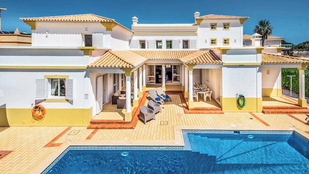 Ein großes Haus mit Swimmingpool, Sitzgelegenheiten im Freien und einer überdachten Terrasse.