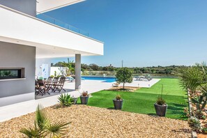 A modern house with a pool, outdoor seating, and a well-maintained lawn.