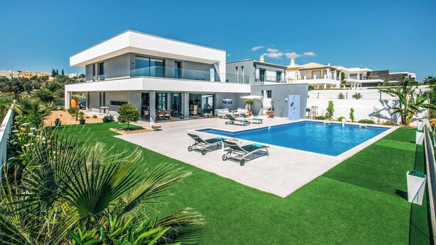 Una casa moderna de dos pisos con piscina, un patio cubierto y un césped bien cuidado.