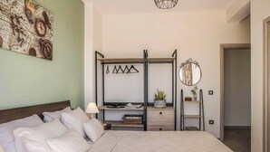 A bedroom with a bed, a nightstand, a dresser, a mirror, and a wall-mounted shelf with a plant. - Villa Elaion (Kefalonia)