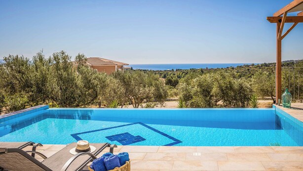 A swimming pool with a clear view of the sea, surrounded by greenery and a pergola. - Villa Elaion (Kefalonia)