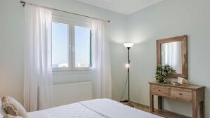 Un dormitorio con cama, mesita de noche, espejo y ventana con cortinas.