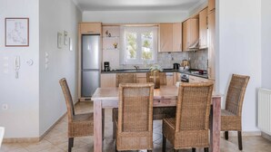 Una cocina moderna con armarios de madera clara, una isla central con sillas y un ventanal que proporciona luz natural.