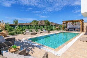 A poolside area with lounge chairs, a pergola, and a small bar area.