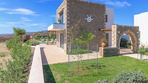 A modern house with a stone facade, a small garden, and a clear view of the surrounding landscape. - Villa Elios Residence (Rhodes)