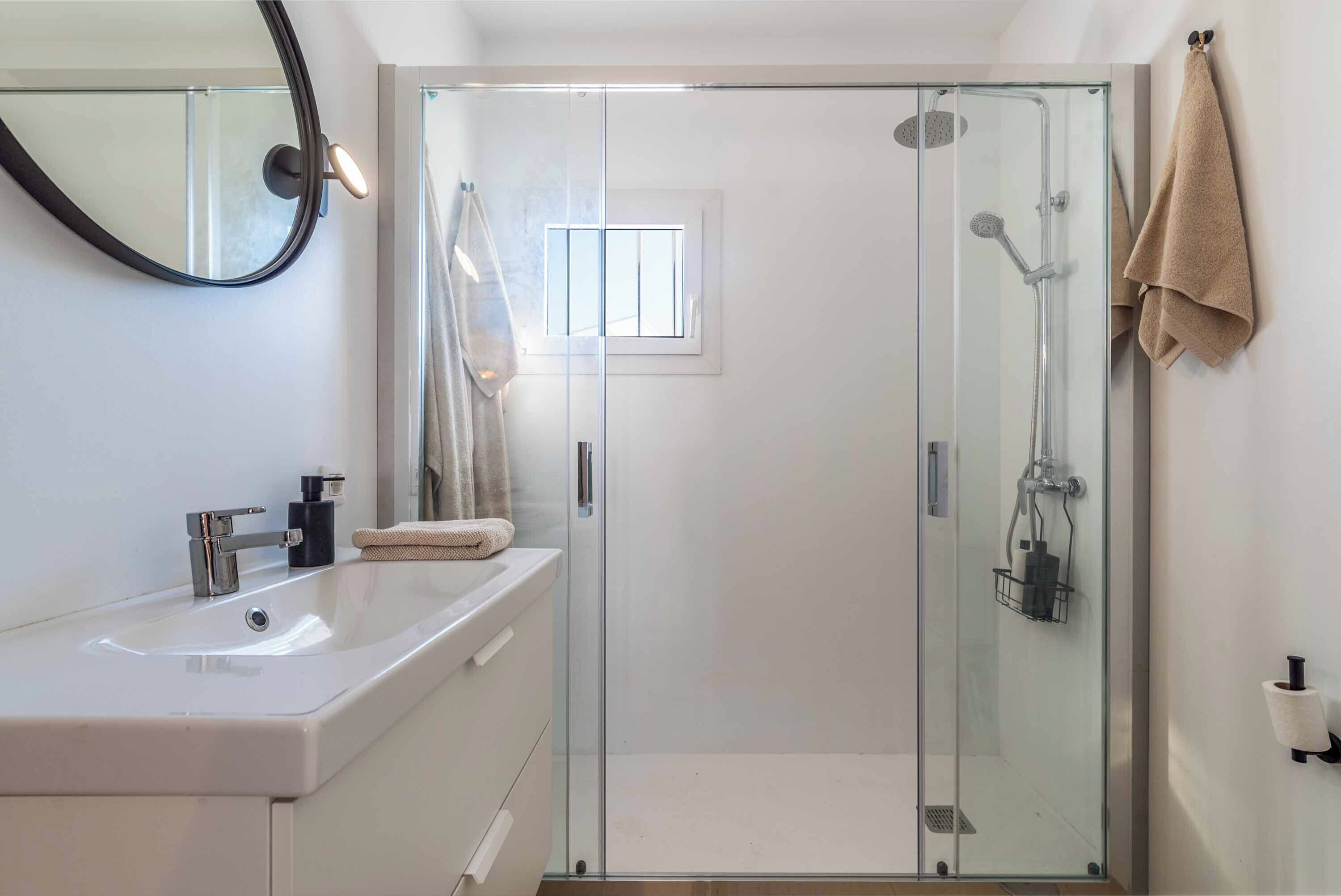 Un baño moderno con cabina de ducha de vidrio, un lavamanos blanco y un perchero para toallas.