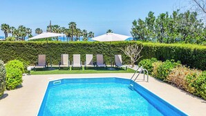 A rectangular swimming pool with a tiled edge, surrounded by a low hedge and a paved walkway. - Villa Lara Latchi (Polis)