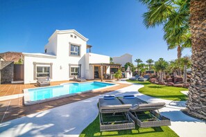 A modern house with a swimming pool, outdoor seating, and palm trees. - Villa Lucero (Yaiza)