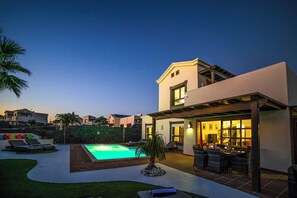 A modern house with a swimming pool, outdoor seating, and a patio area.