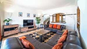 A modern living room with a sofa, coffee table, TV, and a staircase. - Villa Lucero (Yaiza)