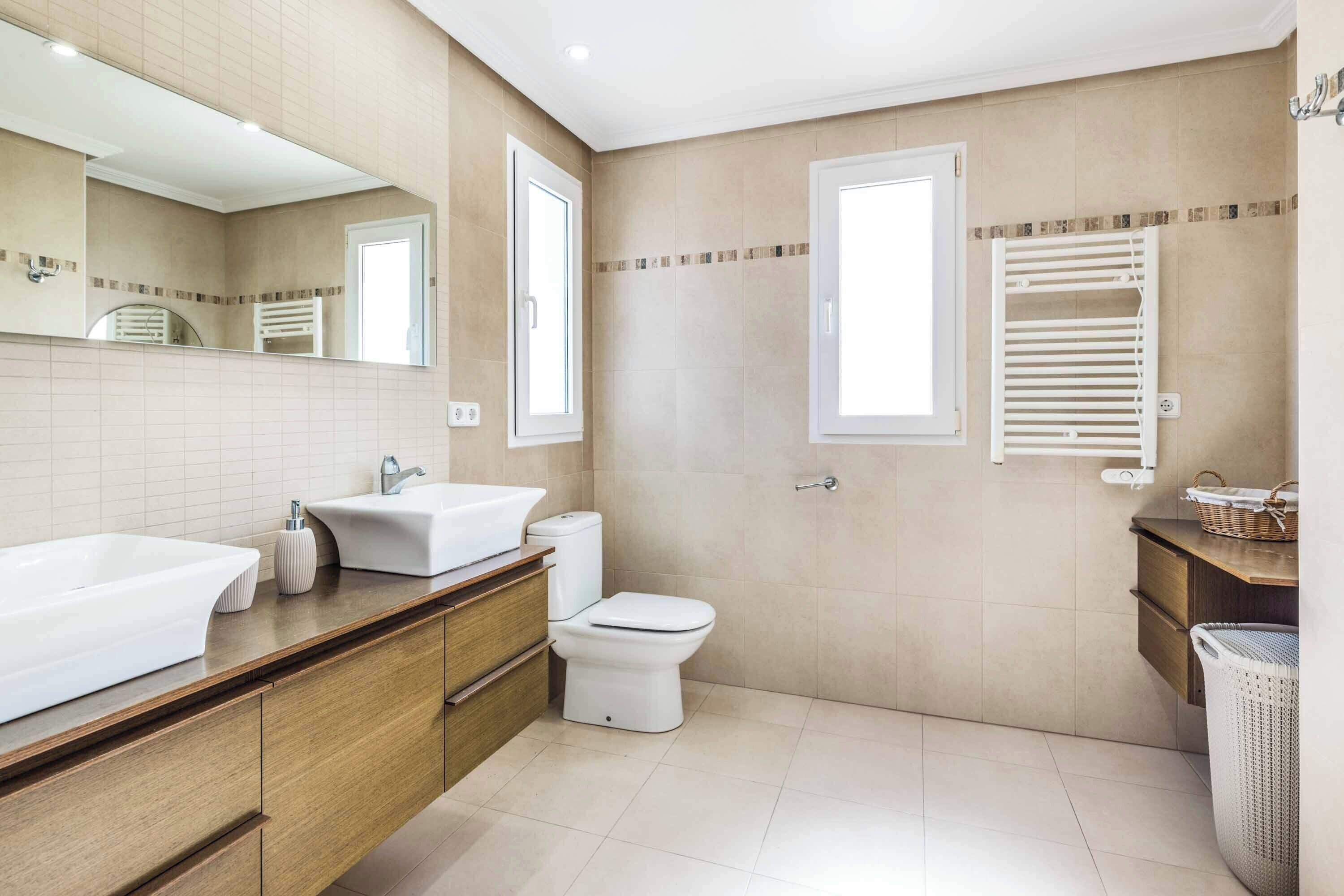 A modern bathroom with a large sink, toilet, and a mirror.
