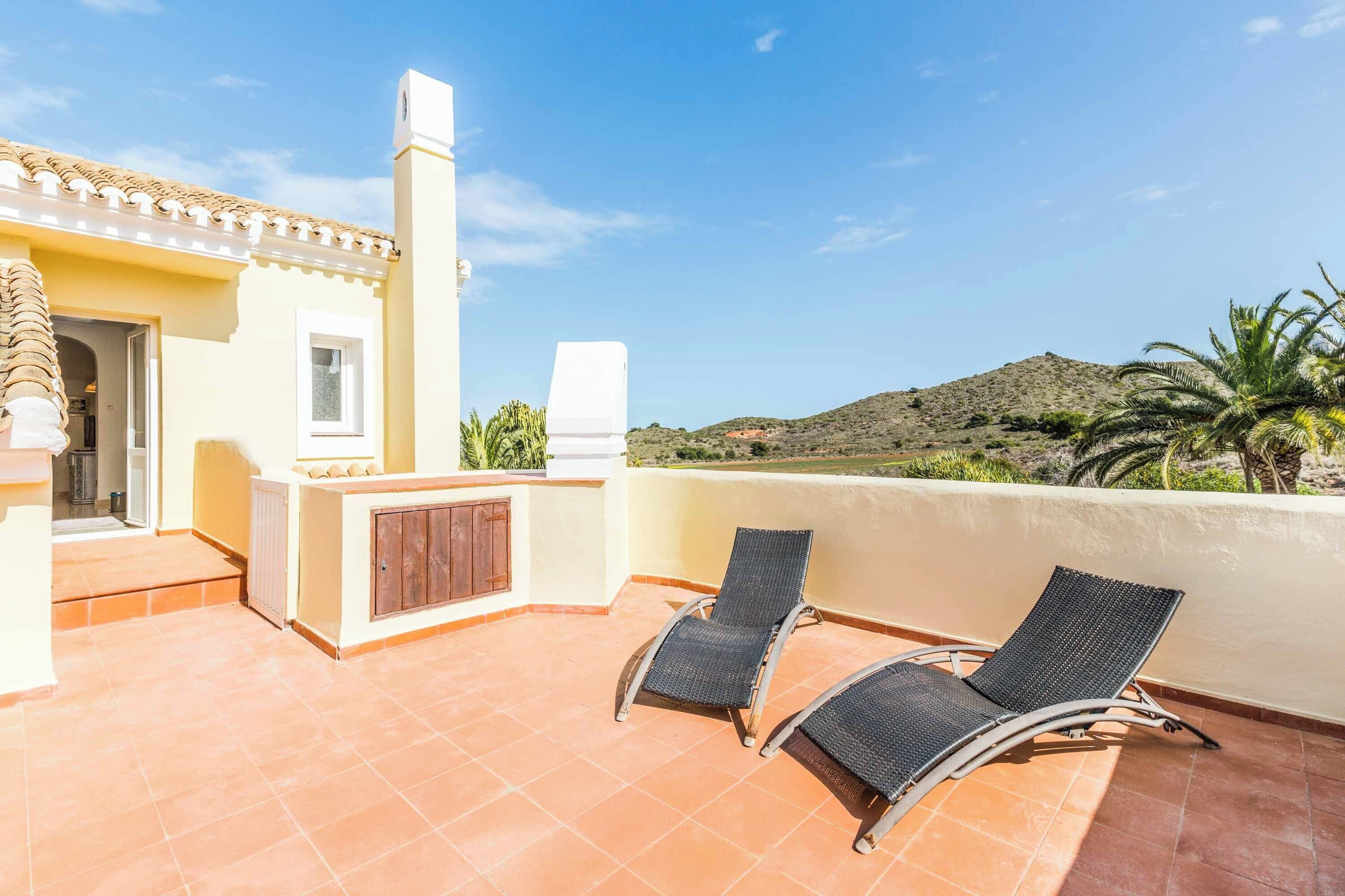 Una terraza en la azotea con dos sillones de descanso, una zona de barbacoa y vistas del paisaje circundante.