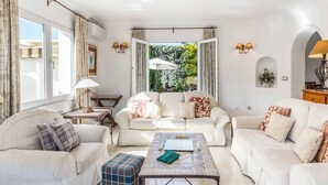 A spacious living room with a large sofa set, a coffee table, and a view of a garden through an open door. - Villa Las Brisas 87 (Cartagena)
