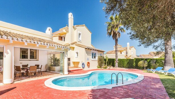 Une piscine dotée d’une terrasse carrelée, de chaises longues et d’un espace extérieur aménagé avec du mobilier de jardin.