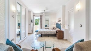 Une chambre d’hôtel moderne avec un lit, une table en verre, un canapé et un balcon.