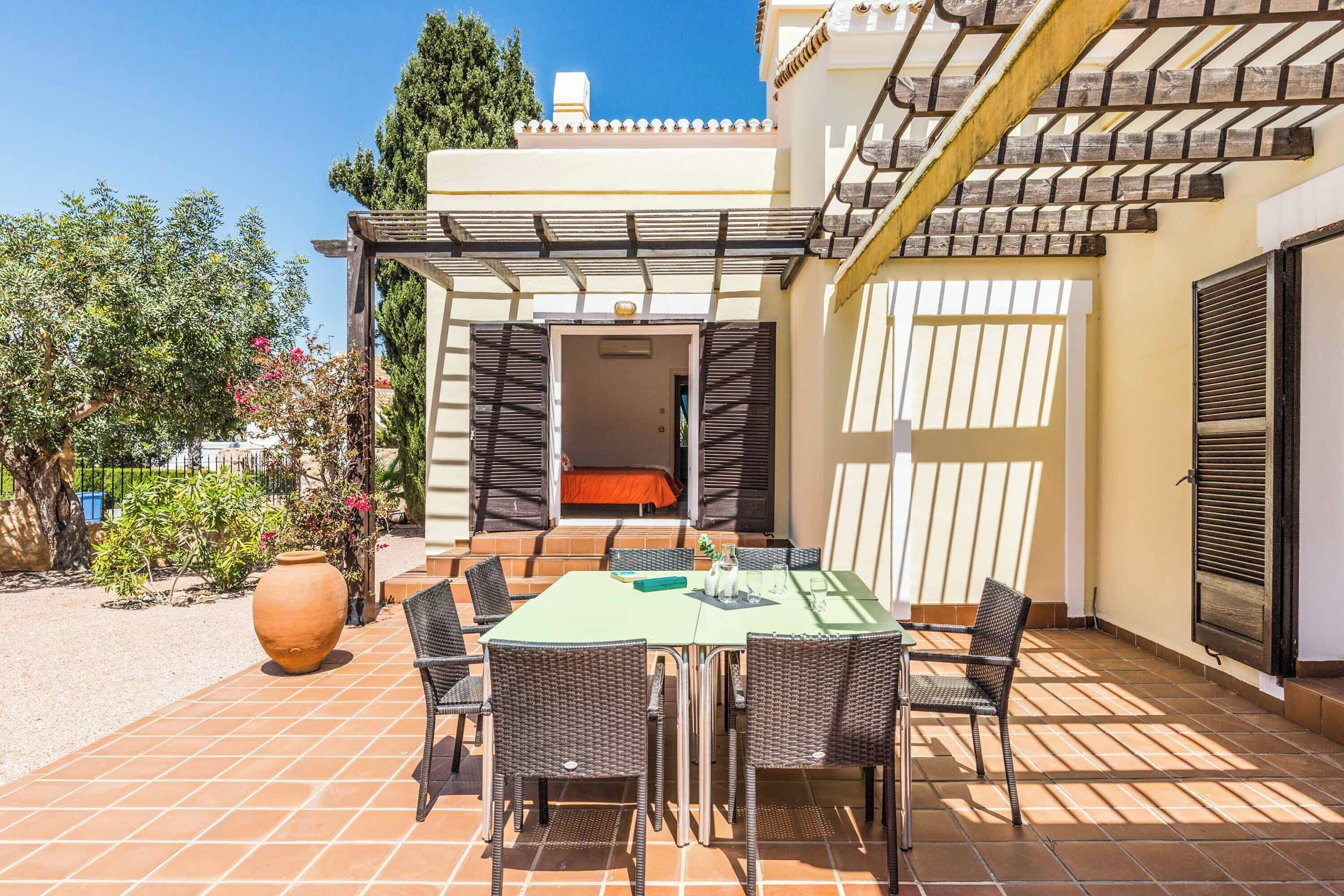 An outdoor patio with a table and chairs, a large vase, and a pergola structure.