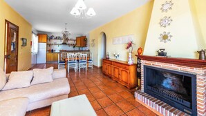 A living room with a sofa, a fireplace, and a kitchen in the background. - Villa Carmela Nerja (Nerja)