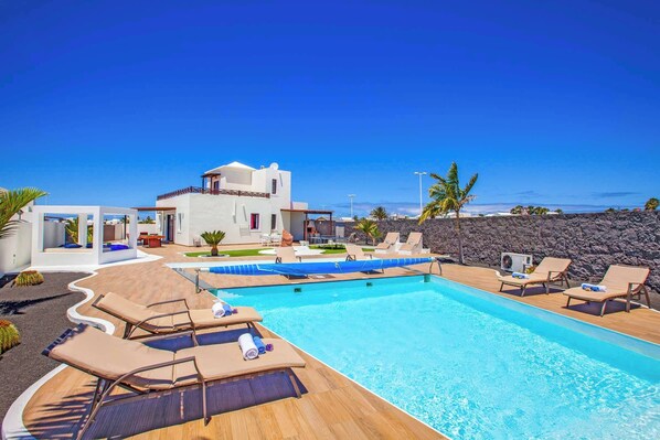 A modern pool area with lounge chairs and a clear view of the ocean. - Villa Esmeralda (Yaiza)