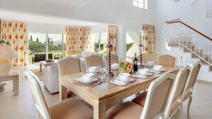 A dining area with a wooden table set for six, surrounded by wicker chairs.