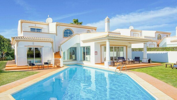 A modern two-story house with a swimming pool, large windows, and a well-maintained lawn.
