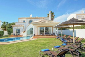 A modern villa with a swimming pool, outdoor seating, and a thatched umbrella. - Villa Ceylon (Albufeira)