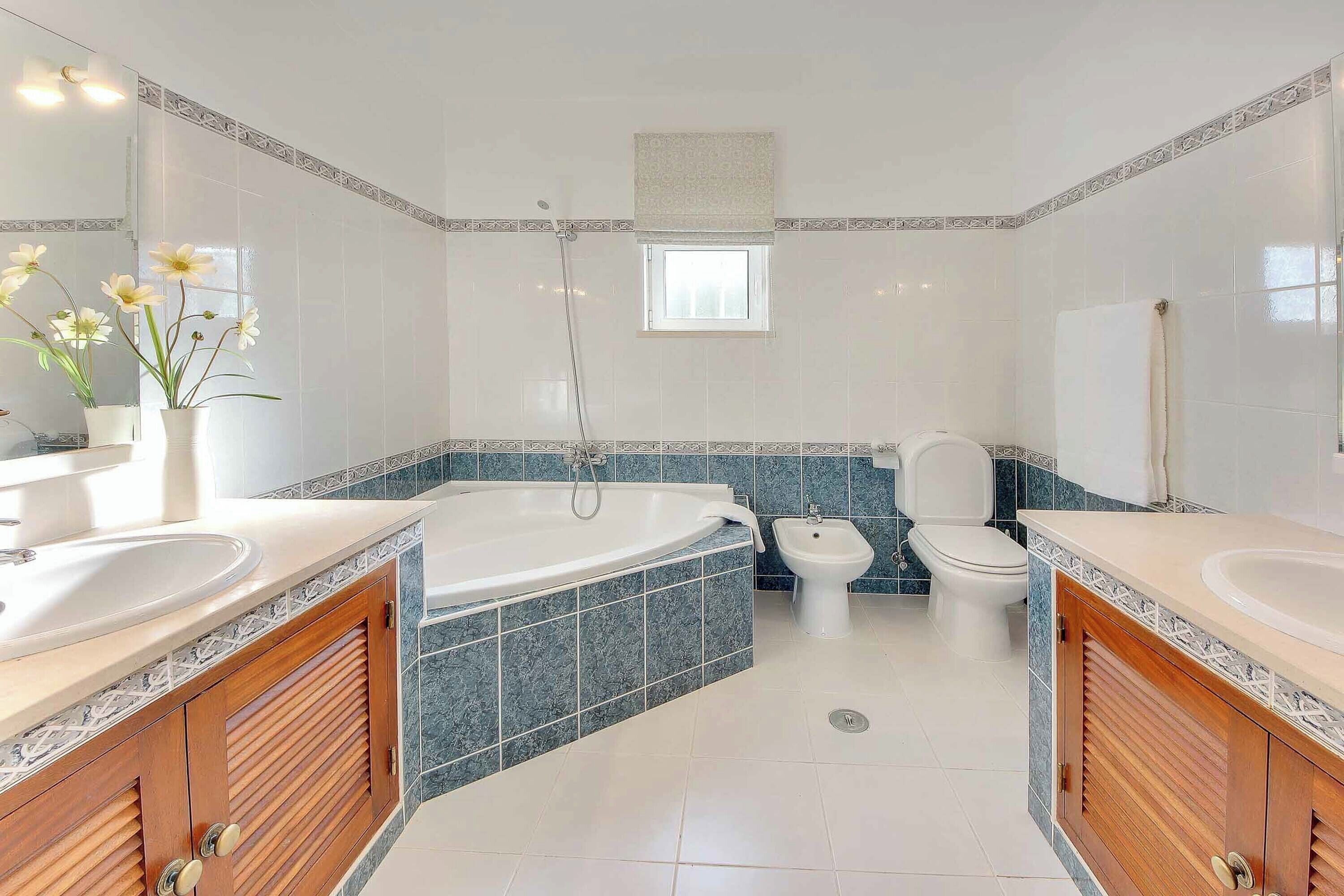 Une salle de bain moderne avec une baignoire, deux lavabos, des toilettes et une fenêtre.