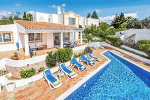 A poolside area with lounge chairs, a covered seating area, and a swimming pool. - Villa Buganvilia (Albufeira)