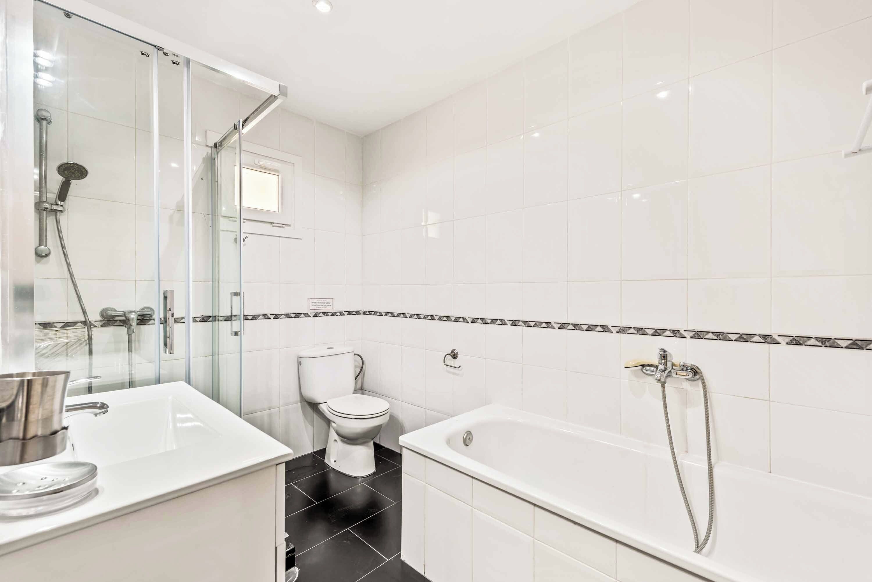 A modern bathroom with a glass-enclosed shower, a white sink, and a bathtub with a handheld showerhead.