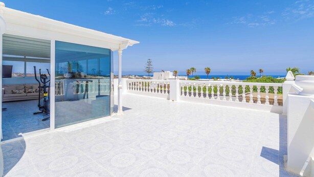 Ein moderner Balkon mit Glasveranda, einer Sitzecke und Sportgeräten.