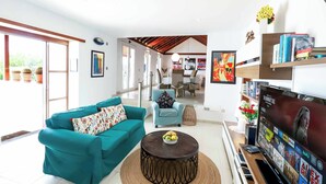 A spacious living room with a teal sofa, a coffee table, and a flat-screen TV. - Villa Dos Piedras (Tías)