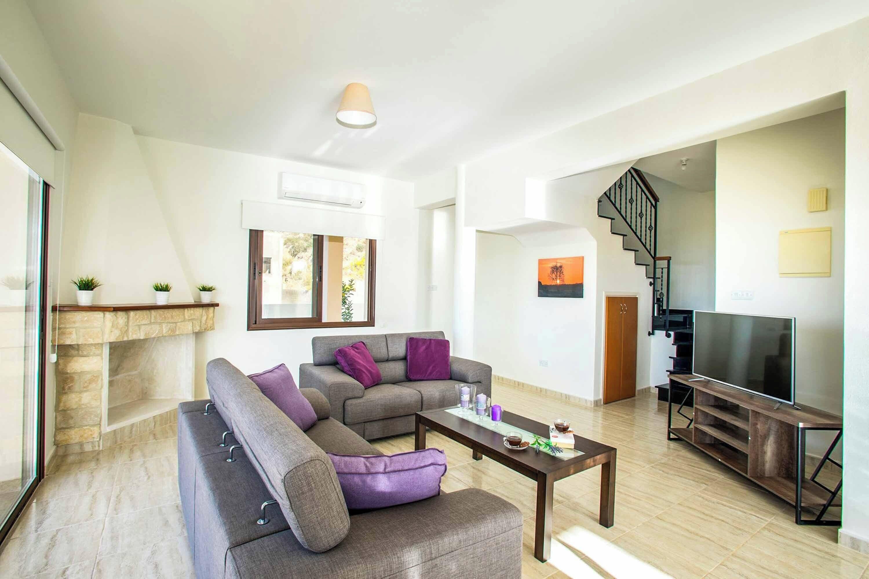 A modern living room with a grey sectional sofa, a coffee table, and a flat-screen TV on a wooden stand.