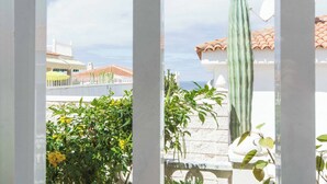 A view through a window with a cactus, a white building, and a tiled roof. - Villa Buganvilla Vistas (Adeje)