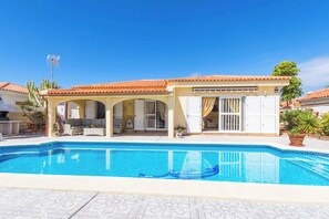 A house with a swimming pool, a covered patio, and a garden.