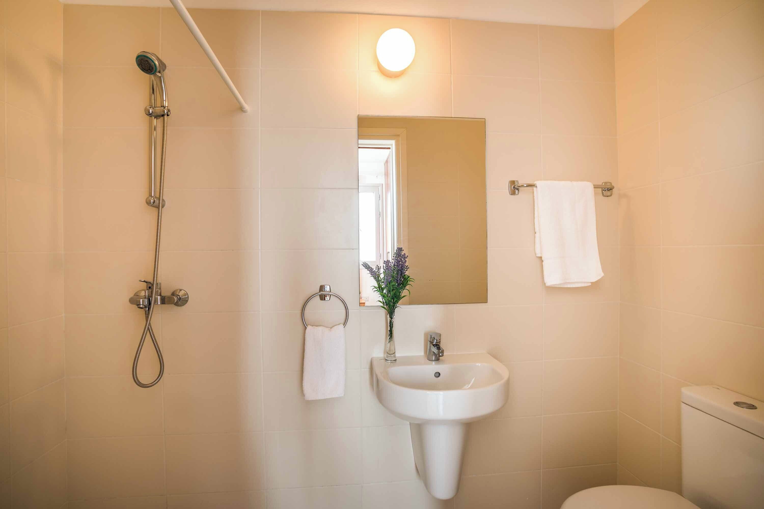 A bathroom with a shower, sink, toilet, and a mirror.