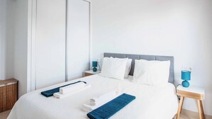 A hotel room with a bed, two nightstands, a blue lamp, and a white wall. - Vista Rey (Yaiza)