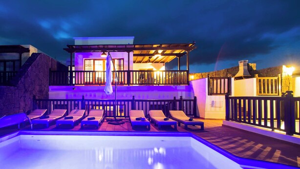 A swimming pool with lounge chairs and a building with a balcony. - Vista Rey (Yaiza)