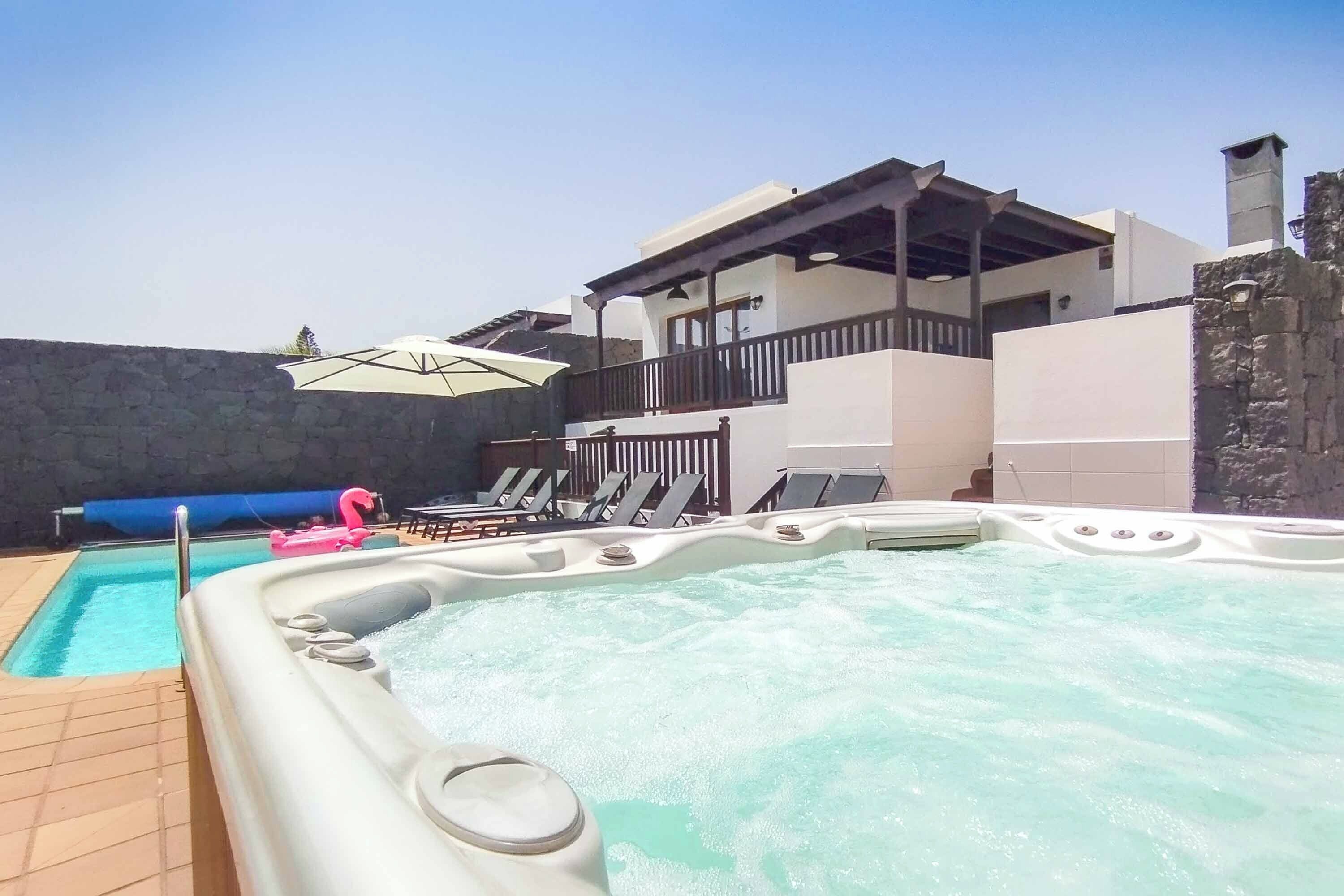 A swimming pool with hot tubs, lounge chairs, and umbrellas.