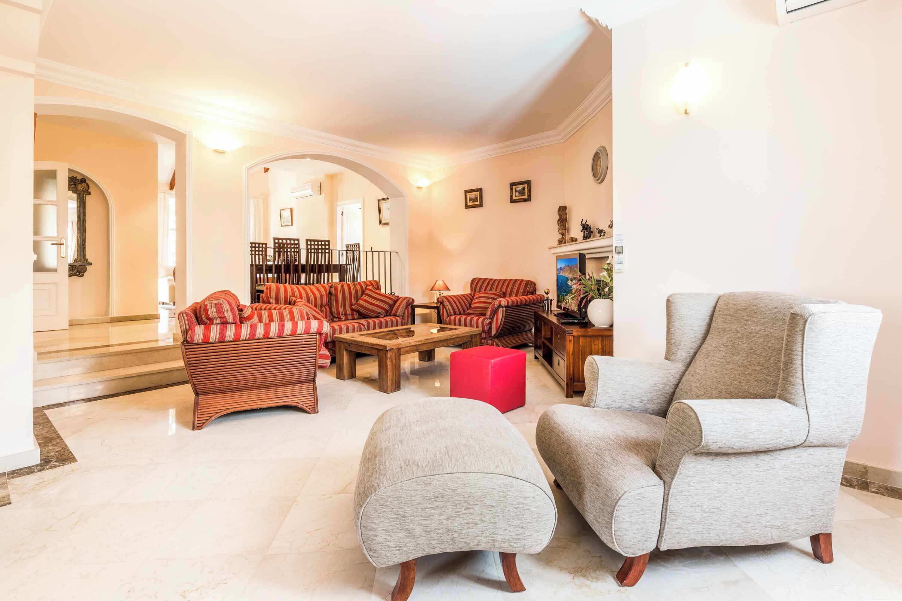 A spacious living room with a sofa set, a coffee table, and a grey armchair.