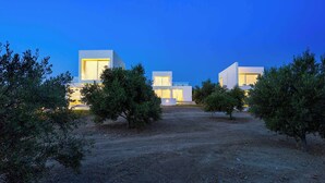 Complejo moderno de edificios con varias estructuras, rodeado de árboles y un sendero de tierra.