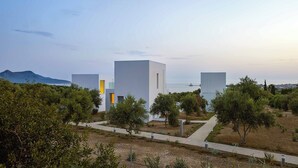 Un complejo moderno de edificios con un diseño minimalista, rodeado de vegetación y una vista despejada del mar.