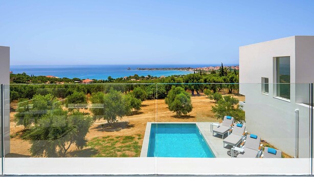 Un área de piscina moderna con vistas despejadas al mar y al paisaje circundante.