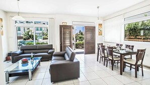 Ein modernes Wohnzimmer mit einer Couch, einem Glastisch und einem Essbereich mit Tisch und Stühlen.