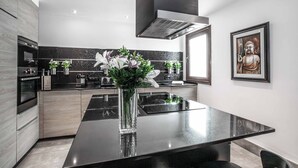 A modern kitchen with a black countertop, stainless steel appliances, and a vase with flowers. - Villa Xian (Yaiza)