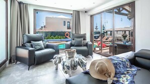 A modern living room with a pool view, two sofas, a coffee table, and a large window. - Villa Xian (Yaiza)