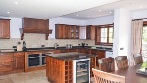 A spacious kitchen with wooden cabinets, a central island, and built-in appliances. - Villa Buena Vista Bocaina (Yaiza)