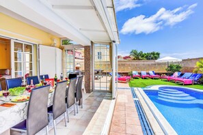 Un espace extérieur aménagé pour les repas, avec une piscine et des chaises longues.