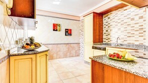Una cocina con frutero, pileta y salpicadero de azulejos.