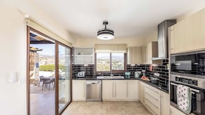 A modern kitchen with a dishwasher, oven, and a view of the outdoors. - Villa Cleco (Pegeia)