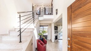 A modern interior with a staircase, red chairs, and a wooden door. - Villa Cleco (Pegeia)