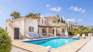 A poolside area with a swimming pool, lounge chairs, and a staircase leading to a building. - Villa Cleco (Pegeia)